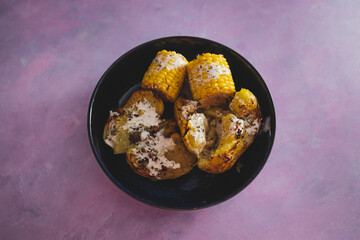 vegan roast potatoes with dairy-free cheesy sauce and corn on the cobs, healthy plant-based food