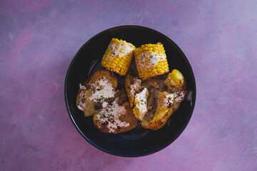 vegan roast potatoes with dairy-free cheesy sauce and corn on the cobs, healthy plant-based food