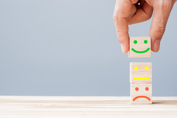 Hand holding smile face symbol on wooden cube blocks. Emotion, Service rating, ranking, customer review, satisfaction and feedback concept