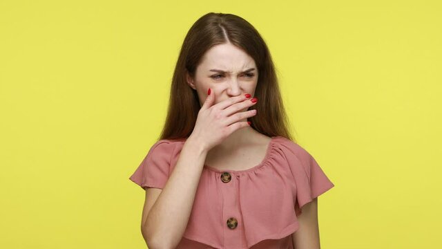 Unhappy woman in elegant dress holding her breath grabbing nose with fingers, feeling unpleasant odor, disgusting smell of farting and dirt. Indoor studio shot isolated on yellow background.