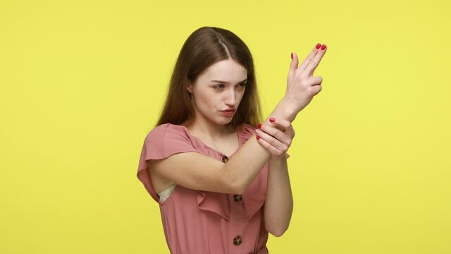 Young attractive feminine girl with brown hair in dress making choice, pointing around with finger gun gesture, shooting killing with hand pistol. Indoor studio shot isolated on yellow background.