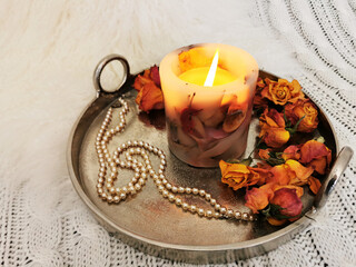Closeup shot of a decorative candle with beads and dried flowers on a tray