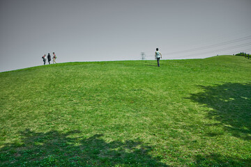 公園の丘に登る家族と一人の男性