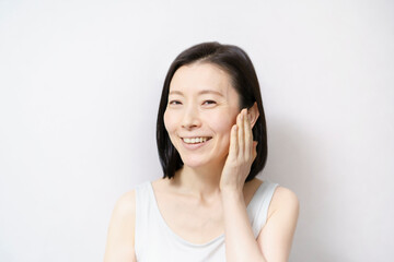 顔を触る日本人女性（40-50代のイメージ）