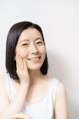 顔を触る日本人女性（40-50代のイメージ）