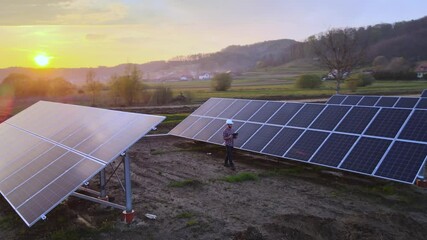 Technical engineer analysing solar farm panels at sunset, future sustainable job - Powered by Adobe