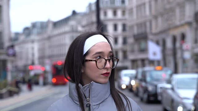 Cute girl standing in street of London, waiting for someone, looking around at her surroundings