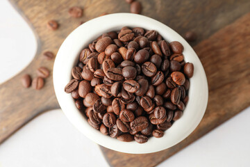 Bowl with coffee beans on light background