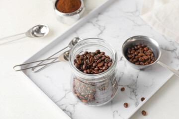 Jar and pot with coffee beans on light background