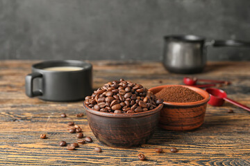 Bowls with coffee beans and powder on wooden background