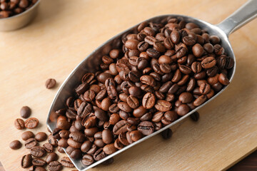Scoop with coffee beans on wooden background