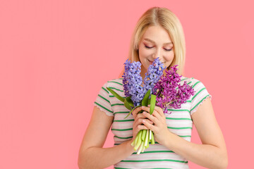 Beautiful young woman with hyacinth flowers on color background