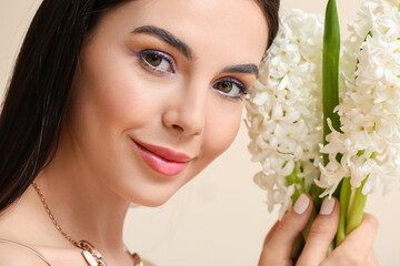 Beautiful young woman with hyacinth flowers on light background