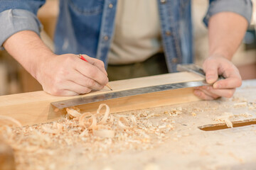 Fototapeta na wymiar Carpenters hands taking measurement of a wooden plank