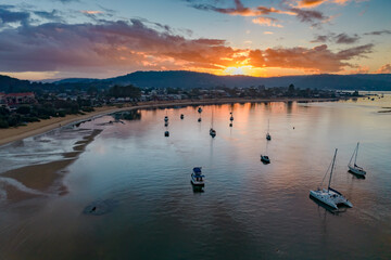 Fototapeta premium Aerial sunrise waterscape with boats and cloud cover