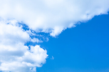 Soft cumulus clouds floating over bright and clear blue sky on sunny day. Pure white cloudscape scene with natural sunlight in summer. Cloudy nature view background with copy space. Tranquil concept.
