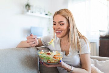 Obraz na płótnie Canvas Healthy lifestyle woman eating salad smiling happy outdoors on beautiful day. Young female eating healthy food laughing and relaxing in sofa.