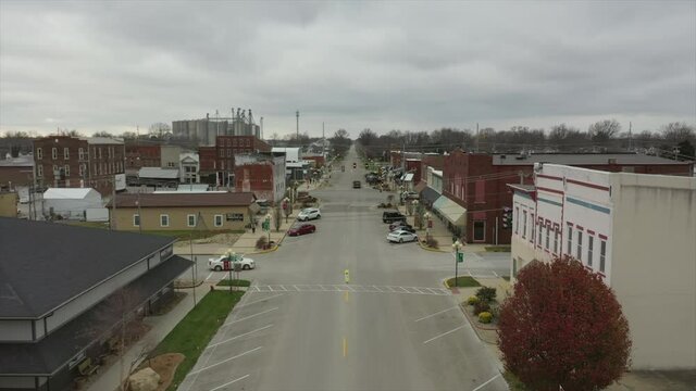 This is an aerial shot going down main street of a small hallmark town in the country in the winter.
