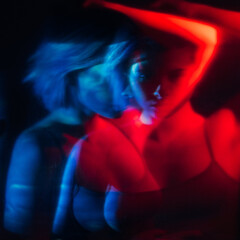 Mental disorder. Abstract portrait. Schizophrenia depression. Defocused double exposure silhouette of disturbed anxious woman in red blue neon light on aged black background.