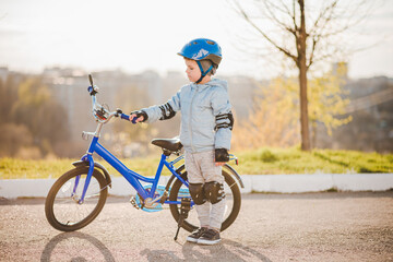 A child in a helmet learns to ride a bike on a sunny day at sunset