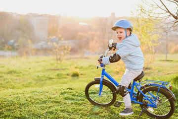 Fototapeta premium Little boy in helmet rides a bicycle on a sunny day
