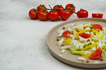 fresh summer vegetable salad with peking cabbage, cherry tomatoes, green peas and yellow bell pepper on a ceramic plate