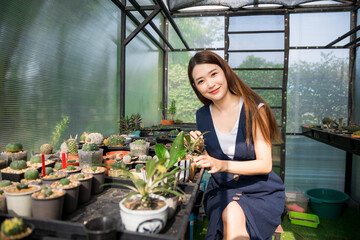 Young cute asian woman working in house plant. Asian female taking care of the tree in greenhouse. Startup small business work from home concept.