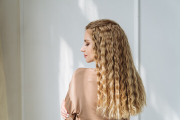 an attractive young woman with blonde hair and long curly hair. curled blonde hair in a natural light brown shade. the concept of hair care