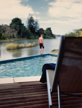 Boy walking along side of swimming pool overlooking Te Puna Estuary