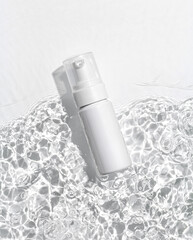White cosmetic bottle on the water surface. Blank label for branding mock-up. Summer water pool...