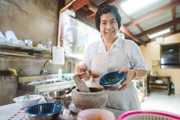 Authentic portrait asian elderly woman cooking local traditional thai style food.