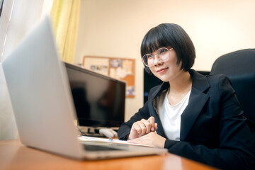 Young adult asian woman using laptop computer for video call work at home on day.