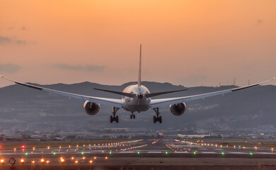 夕陽を背景に着陸する飛行機のイメージ