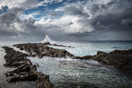 Stormy skies and waves crashing onto rocky coast