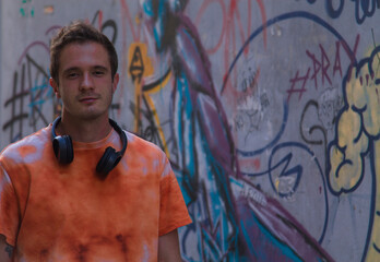 young man with headphones on public wall with graffiti not subject to copyright
