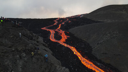 Fototapeta premium lava eruption volcano with snowy mountains, Aerial view Hot lava and magma coming out of the crater, April 2021 