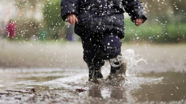 Kid splashing into water mud puddles