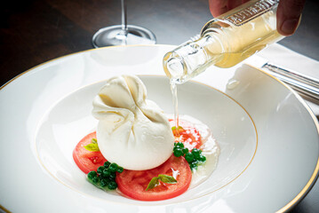 Burrata italian cheese snack with tomeatoes served on white plate