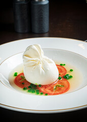 Burrata italian cheese snack with tomeatoes served on white plate
