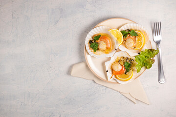 Scallops with lemon on white background with napkin and fork. Baked scallops with caviar and creamy garlic sauce in white plate. Top view. Copy space.