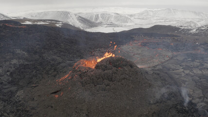 Naklejka premium lava eruption volcano with snowy mountains, Aerial view Hot lava and magma coming out of the crater, April 2021 