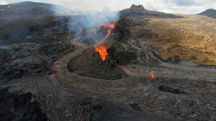 Fototapeta premium lava eruption volcano with snowy mountains, Aerial view Hot lava and magma coming out of the crater, April 2021 
