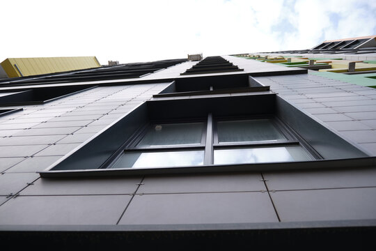 wall of office building made of metal plates with windows. Detail of modern residential building windows on ceramic ventilated facade.