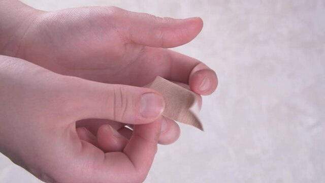 Pasting a wart or fungus on a young woman's finger with adhesive plaster.