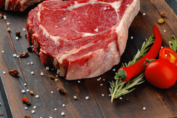Raw rib eye steak on brown wooden board