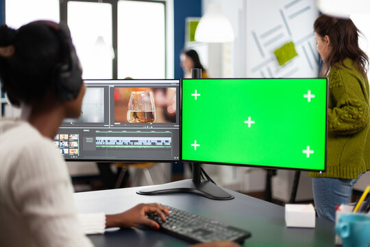 Black woman video editor developing new project film montage looking at greenscreen, chroma key isolated display of computer, sitting in creative agency. Creator processing movie with modern software