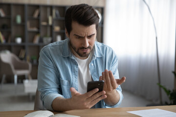 Close up unhappy dissatisfied businessman looking at phone screen, reading bad news in message,...
