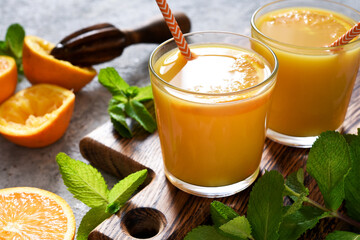 Fresh squeezed orange juice on a gray concrete background with mint.