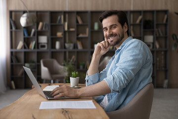 Portrait smiling successful businessman sitting at desk with laptop, confident happy entrepreneur...