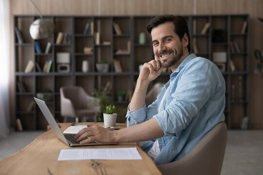Portrait smiling successful businessman sitting at desk with laptop, confident happy entrepreneur looking at camera, positive man student or freelancer working online on project, profile picture